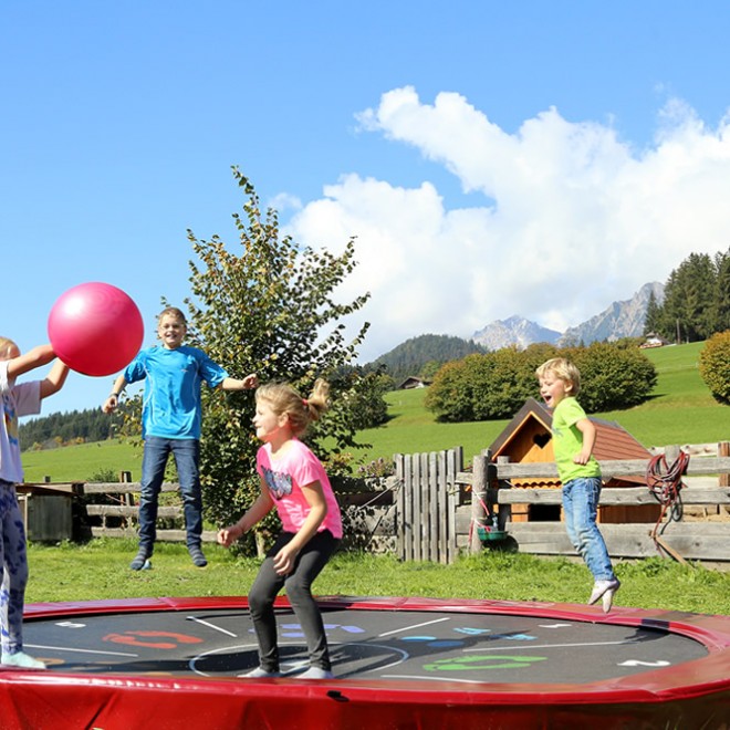 Kinder toben sich am Trampolin im Garten aus